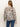 A person with long, straight brown hair is shown from the back, wearing Sanctuary Clothing’s wild dreamer blouse mother leo in a black and beige animal print and blue jeans.
