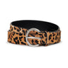 The Riot Leopard Belt Leopard by Sanctuary Clothing is shown coiled on a white background. It features a tan base with black and brown spots, a round silver buckle, and a bold leopard print pattern.