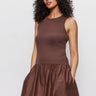A woman with curly hair models the Sanctuary Clothing "take me away midi dress mesa"—a sleeveless, brown, fitted-top dress with a gathered skirt and pockets—standing against a plain background.