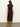 A woman with wavy brown hair wears the Sanctuary Clothing "autumns best sweater dress cocoa plaid," a calf-length, diamond-patterned dress with cap sleeves, paired with tan knee-high suede boots on a grey floor against a plain light wall.