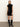 A woman with straight blonde hair stands against a plain background, wearing Sanctuary Clothing's "An Affair to Remember Dress" in black—a short, sleeveless sequin dress—paired with knee-high black heeled boots.