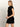A woman with straight blonde hair models Sanctuary Clothing’s "An Affair to Remember Dress" in black, featuring short sleeves and sequins, standing in profile against a plain light background.