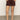 A person stands with hands in the pockets of Sanctuary Clothing's Renegade Short Mesa, styled with a patterned top and brown sandals against a plain light background.