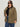 A woman in dark sunglasses, a black top, blue jeans, and the Sanctuary Clothing barn jacket burnt olive extended sizing stands against a plain light background.