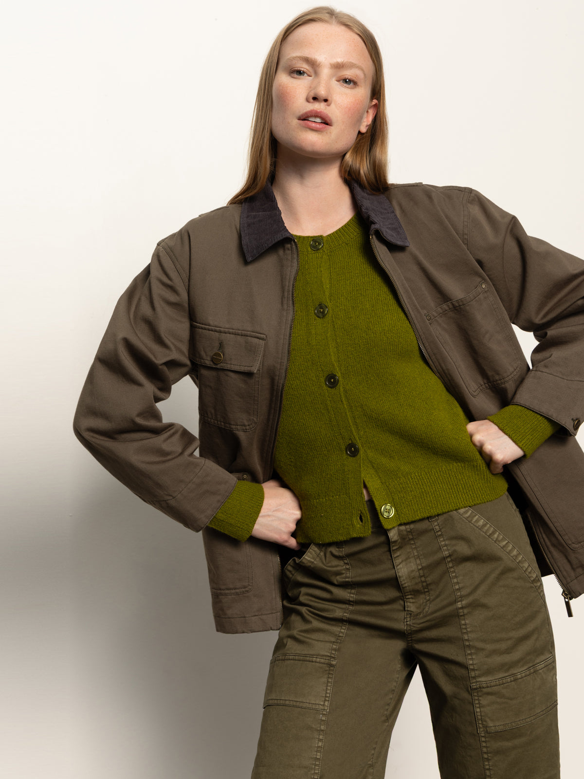 A woman with long blonde hair wears the Sanctuary Clothing barn jacket in burnt olive, paired with matching pants, posing confidently against a plain, light background.