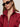 A woman wears black oval sunglasses, silver hoop earrings, and the Sanctuary Clothing satin track jacket in crimson, featuring white shoulder stripes, standing against a neutral background.