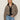 A woman with straight blonde hair and a relaxed expression models the Sanctuary Clothing cropped barn jacket french kitty—a leopard print jacket with a black collar—over a black top and light blue jeans against a plain background.
