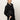 A woman with light hair tied back wears the Sanctuary Clothing coated twill bomber jacket in black and black pants with a white side stripe, standing confidently against a plain white background with one hand in her pocket.
