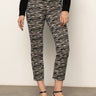 A person wears Sanctuary Clothing's Carnaby Kick Crop Legging Fluid Zebra pants with a black long-sleeve top and black low-heeled shoes, standing against a plain light background.
