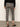 A person stands facing away, wearing Sanctuary Clothing's carnaby kick crop legging fluid zebra pants with a black top and black pointed-toe heels, on a gray floor against an off-white wall.