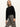 A woman with straight blonde hair wears Sanctuary Clothing’s carnaby kick crop legging fluid zebra pants and a black long-sleeve sweater while standing against a plain white wall.