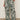 Someone wearing Sanctuary Clothing’s the soft trouser green oasis extended sizing, styled with black sandals and a tucked-in white top, stands against a plain background.