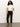 A woman with curly hair stands against a plain background, wearing Sanctuary Clothing’s the marine jeans after hours with a white short-sleeve t-shirt and tan suede ankle boots. She looks at the camera in a relaxed pose with a neutral expression.