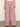 A person models the Sanctuary Clothing marine full length semi high rise pant in galley stripe—pink and white wide-leg pants with front pockets. They're paired with a white top and sandals on a gray floor against a beige backdrop, face not shown.
