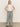 A woman with long, straight blonde hair stands against a plain background wearing Sanctuary Clothing's marine full length semi high rise pant in yacht stripe. Her hands rest on her hips and she's paired the pants with a sleeveless white top and black sandals.