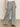 A person stands against a plain background wearing Sanctuary Clothing’s marine full length semi high rise pant in yacht stripe. The gray pinstriped pants are paired with black open-toe sandals; the photo is cropped from the waist down.