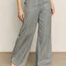 A person stands against a plain background wearing Sanctuary Clothing’s marine full length semi high rise pant in yacht stripe. The gray pinstriped pants are paired with black open-toe sandals; the photo is cropped from the waist down.