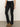 A person wearing black cargo pants with front and side pockets, a white top, and tan suede heeled boots, standing against a plain light background.