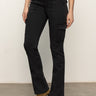 A person wearing black cargo pants with front and side pockets, a white top, and tan suede heeled boots, standing against a plain light background.
