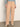 A person stands against a plain wall, wearing Sanctuary Clothing's corduroy marine pant in dusty rose, paired with a light blue long-sleeve top and beige shoes; their head is out of frame.