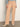 A person wearing Sanctuary Clothing's corduroy marine pant in dusty rose, paired with a light blue long-sleeve top and beige pointed-toe boots, stands against a light background with their face not visible.