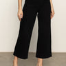 A person models the Sanctuary Clothing soft marine wide leg crop pant in black with black heeled sandals, standing on a concrete floor against a light background. The photo is cropped from the shoulders down.