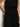 A person stands against a light-colored wall wearing Sanctuary Clothing’s soft marine wide leg crop pant in black and a sleeveless black button-up shirt, with one hand resting in a pocket.