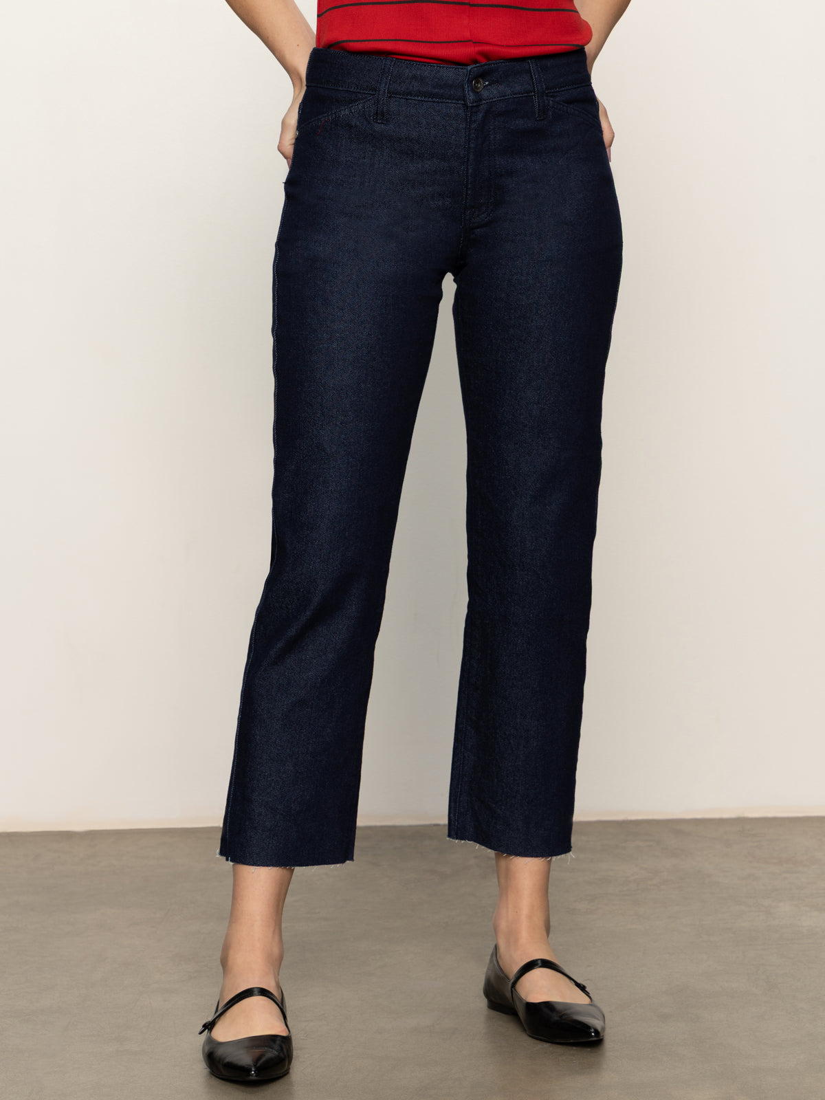 Wearing Sanctuary Clothing’s cadence 90s straight crop plot twist jeans, a person stands against a light wall and gray floor with hands behind their back and face not visible.