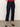Wearing Sanctuary Clothing’s cadence 90s straight crop plot twist jeans, a person stands against a light wall and gray floor with hands behind their back and face not visible.