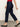 A person wears the Sanctuary Clothing cadence 90s straight crop plot twist jeans, paired with a red top and black flats, walking against a plain light background. Only their lower half is visible.
