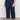 A person stands against a light background wearing Sanctuary Clothing's league crop plot twist extended sizing top, paired with high-waisted dark blue wide-leg jeans with front pockets and black strappy sandals.