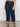 A person stands against a light background wearing Sanctuary Clothing's league crop plot twist extended sizing top, paired with high-waisted dark blue wide-leg jeans with front pockets and black strappy sandals.