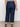 A person stands facing away, wearing Sanctuary Clothing’s league crop plot twist extended sizing: dark blue high-waisted, wide-leg jeans with back pockets, black sandals, and a black-and-white striped sleeveless top.
