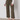 A person wearing Sanctuary Clothing's league crop fatigue pants, paired with a light long-sleeve sweater and white woven flats, stands indoors on a concrete floor against a plain wall.