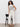 A person with curly hair wears the Sanctuary Clothing league crop light oat top with cream wide-leg pants and black sandals, standing next to a black chair against a plain white wall.