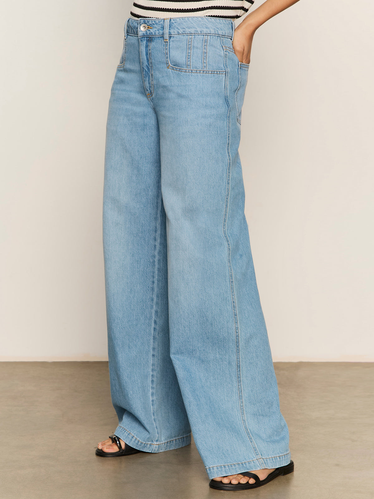 Person wearing Sanctuary Clothing's Highland Wide Leg Standard Rise Jeans in Sail Away, styled with black sandals and a striped top, photographed against a plain light background.