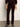 A person indoors wears Sanctuary Clothing„¢s velveteen brook bootcut pant in dark crimson, paired with matching outerwear and heeled ankle boots. Only their lower half is visible against a plain background.
