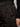 A close-up of someone wearing Sanctuary Clothing's sahara satin tapered pant in black with pleats, their hand in the pocket, paired with a long-sleeve textured black top.
