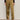 A person stands against a plain light wall wearing Sanctuary Clothing's sahara satin tapered pant in dirty martini, paired with a long-sleeve black top and brown leopard-print shoes. The photo is cropped at the shoulders.