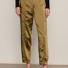 A person stands against a plain light wall wearing Sanctuary Clothing's sahara satin tapered pant in dirty martini, paired with a long-sleeve black top and brown leopard-print shoes. The photo is cropped at the shoulders.