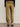 A person faces away, wearing Sanctuary Clothing’s sahara satin tapered pant in dirty martini, featuring back pockets, tapered legs, and paired with a black long-sleeve top and animal-print flats.
