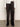 A person wears Sanctuary Clothing’s satin track pant in black with white side stripes, a white long-sleeve shirt with wide cuffs, and black pointed-toe shoes, standing against a plain light background.