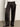 Someone wears the Sanctuary Clothing satin track pant in black, featuring white side panels, paired with a white button-down shirt and black pointed-toe shoes, standing on a gray floor against a plain wall.