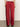 A person stands on a gray floor, waist down, wearing Sanctuary Clothing's satin track pant in crimson with a right-side back zipper pocket, paired with maroon platform shoes.