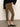 A person stands indoors in Sanctuary Clothing’s Fairway Legging in Dirty Martini, paired with a black sweater and black pointed flats. The image displays the lower half of the body against a plain background.