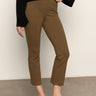 A person stands indoors in Sanctuary Clothing’s Fairway Legging in Dirty Martini, paired with a black sweater and black pointed flats. The image displays the lower half of the body against a plain background.