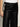 A person wearing Sanctuary Clothing's coated twill track pant in black with an ivory side stripe and drawstring waist, paired with a white top. Only the lower torso and part of one arm are visible.