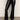 A person wearing Sanctuary Clothing's tango legging black, featuring a beige and black animal print waistband, paired with black heeled ankle boots, stands on a smooth gray floor.