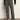 A person stands against a plain wall wearing Sanctuary Clothing’s 90s straight legging burnt olive plaid petites, paired with a black sweater and black ballet flats. Their head is out of frame.