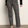 A person stands against a plain wall wearing Sanctuary Clothing’s 90s straight legging burnt olive plaid petites, paired with a black sweater and black ballet flats. Their head is out of frame.